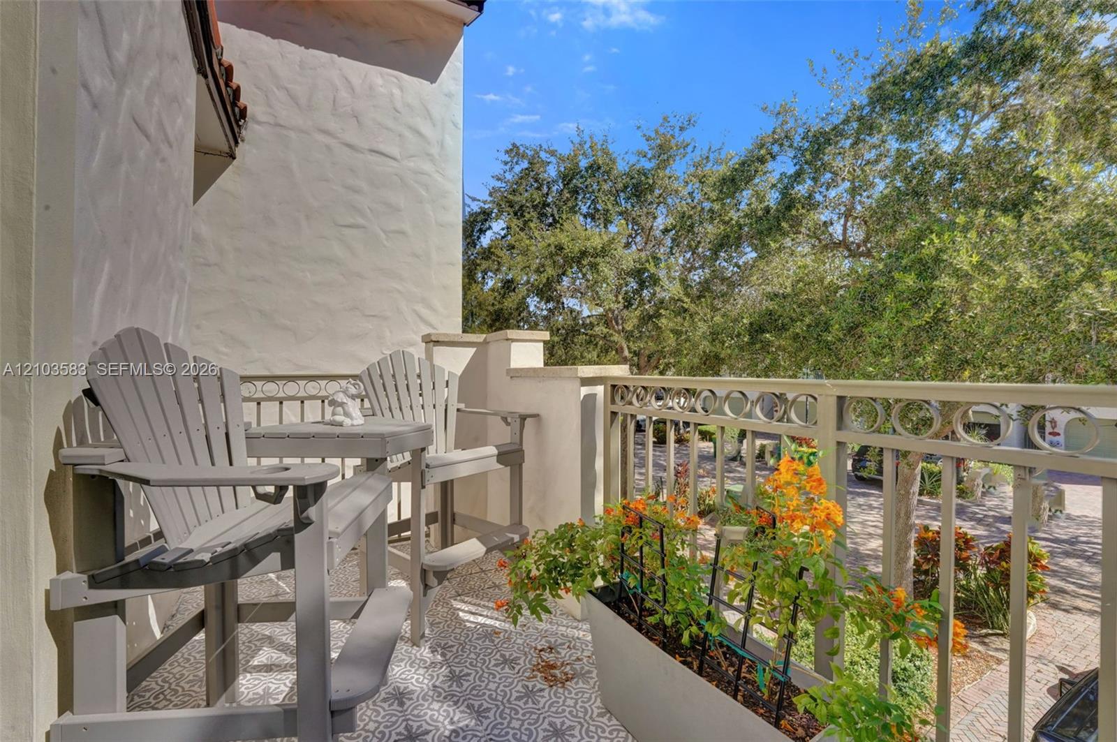 Exterior balcony featuring patterned tile flooring, textured stucco wall, and decorative metal railing