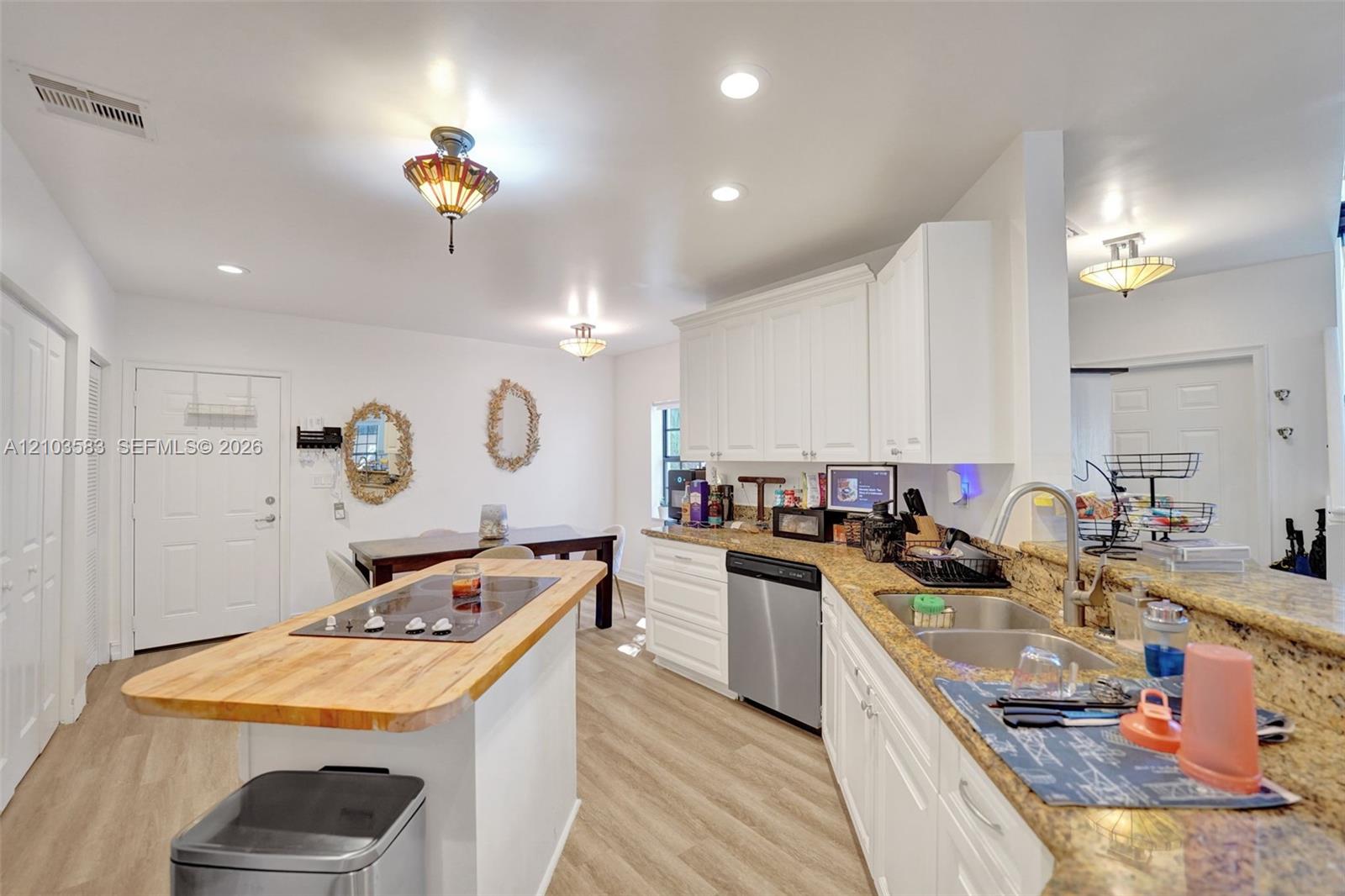 Kitchen featuring white cabinetry, stone-finish countertops, wood-finish flooring, central island with a wood-top surface, and stainless-steel appliances