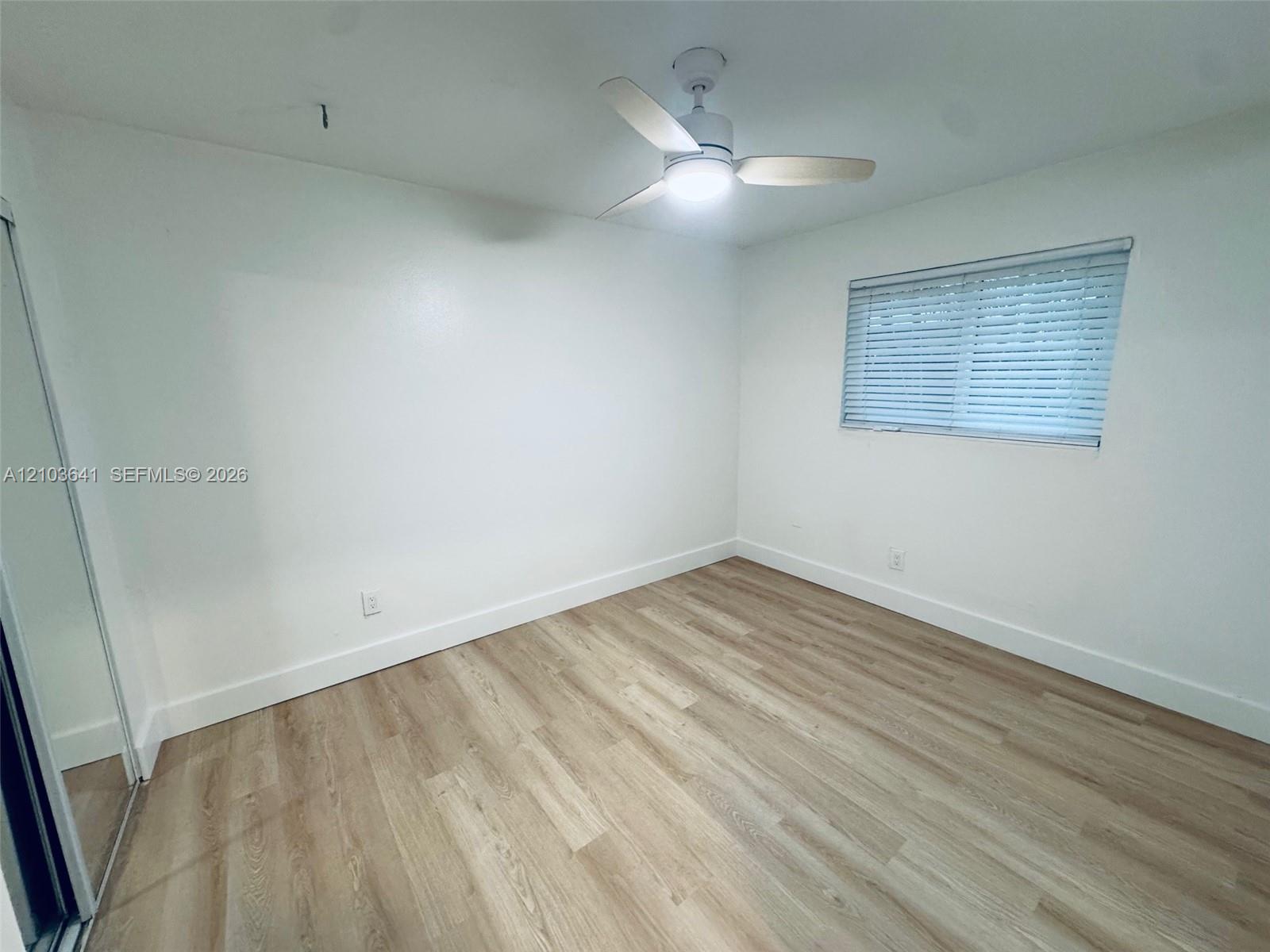 Interior room featuring wood-finish flooring, a ceiling fan with integrated lighting, and horizontal window blinds