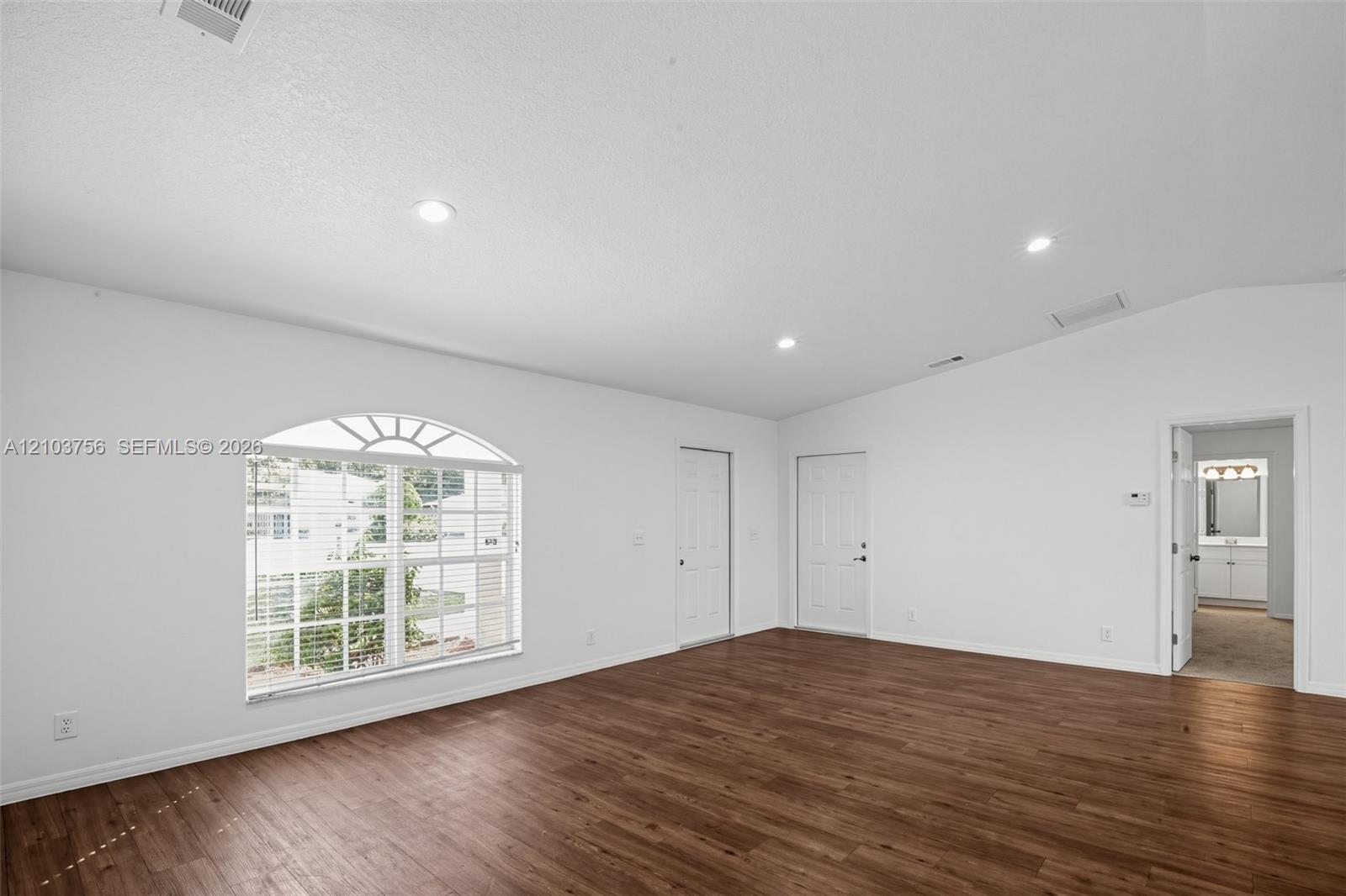 Vaulted ceilings, wood-finish flooring, recessed lighting, and a window featuring an arched transom