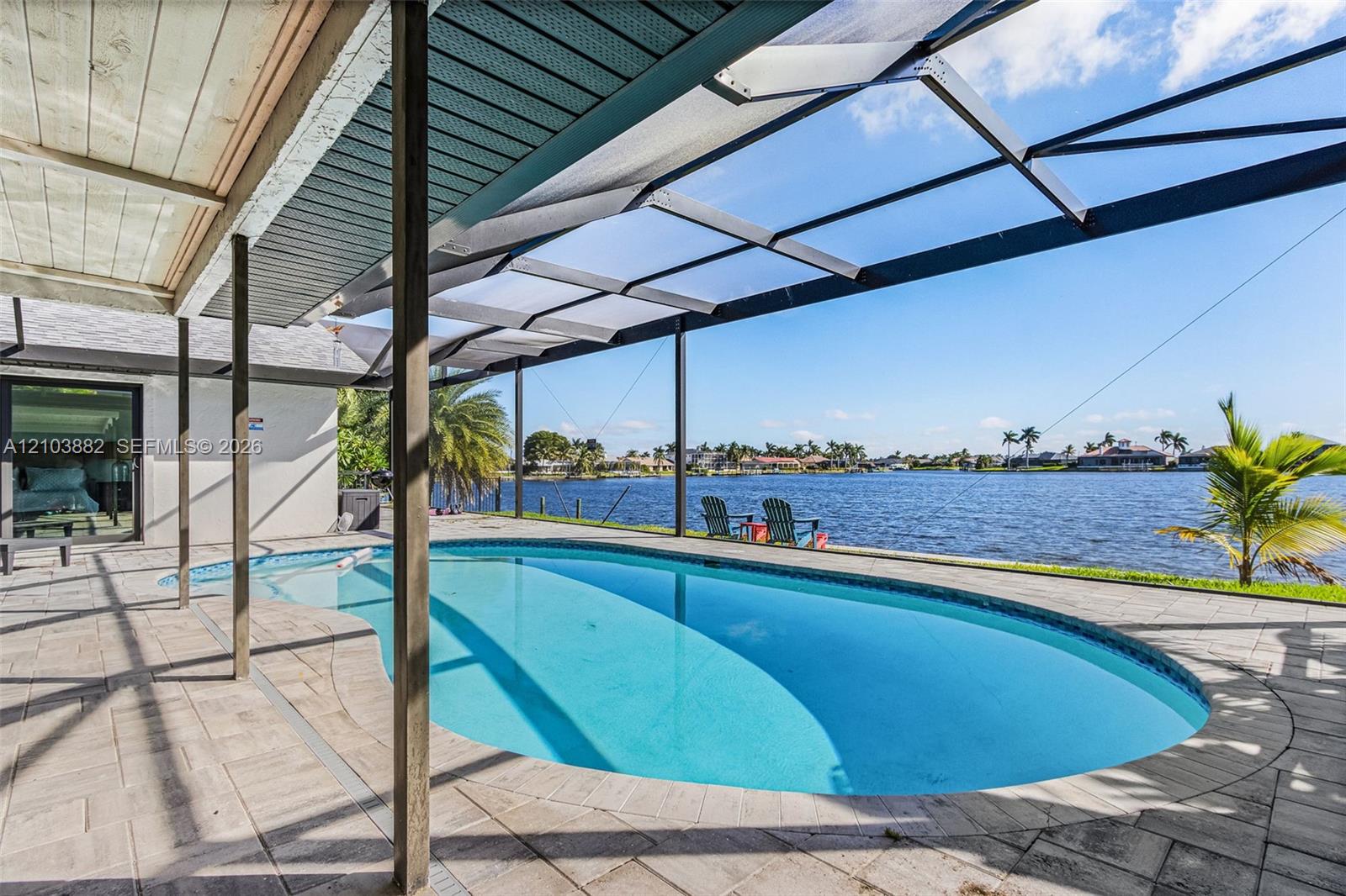Screened lanai featuring a pool with built-in stairs, paver decking, and waterfront positioning