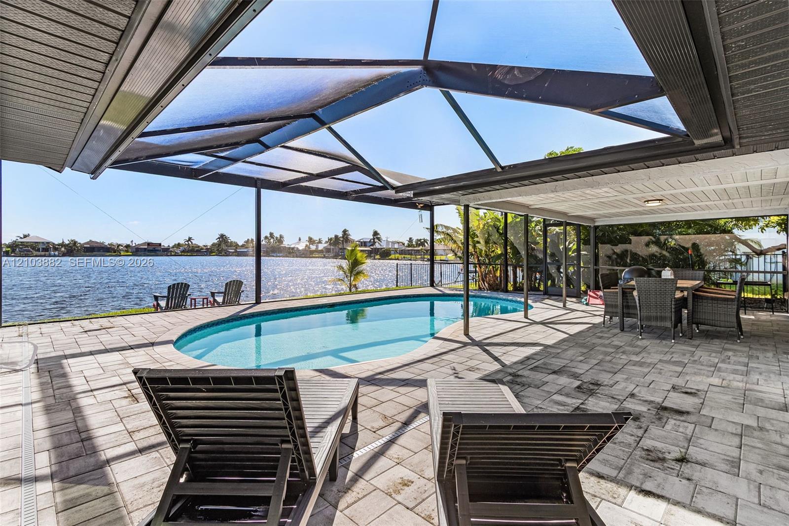 Screen-enclosed patio featuring a paver deck, a kidney-shaped pool, a covered lanai, and waterfront access