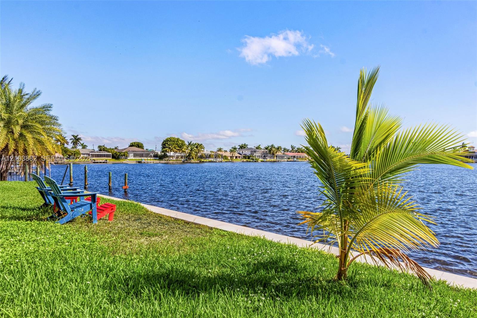 Waterfront lot featuring a concrete seawall, manicured lawn, and mature palm trees