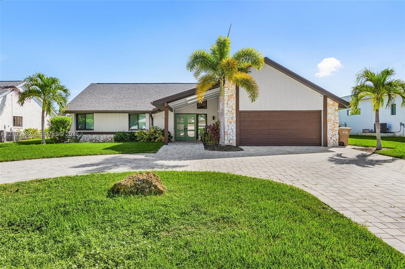 Single-story exterior featuring stone masonry accents, a paved driveway, double-entry doors, and a multi-car garage Single-story exterior featuring stone masonry accents, a paved driveway, double-entry doors, and a multi-car garage