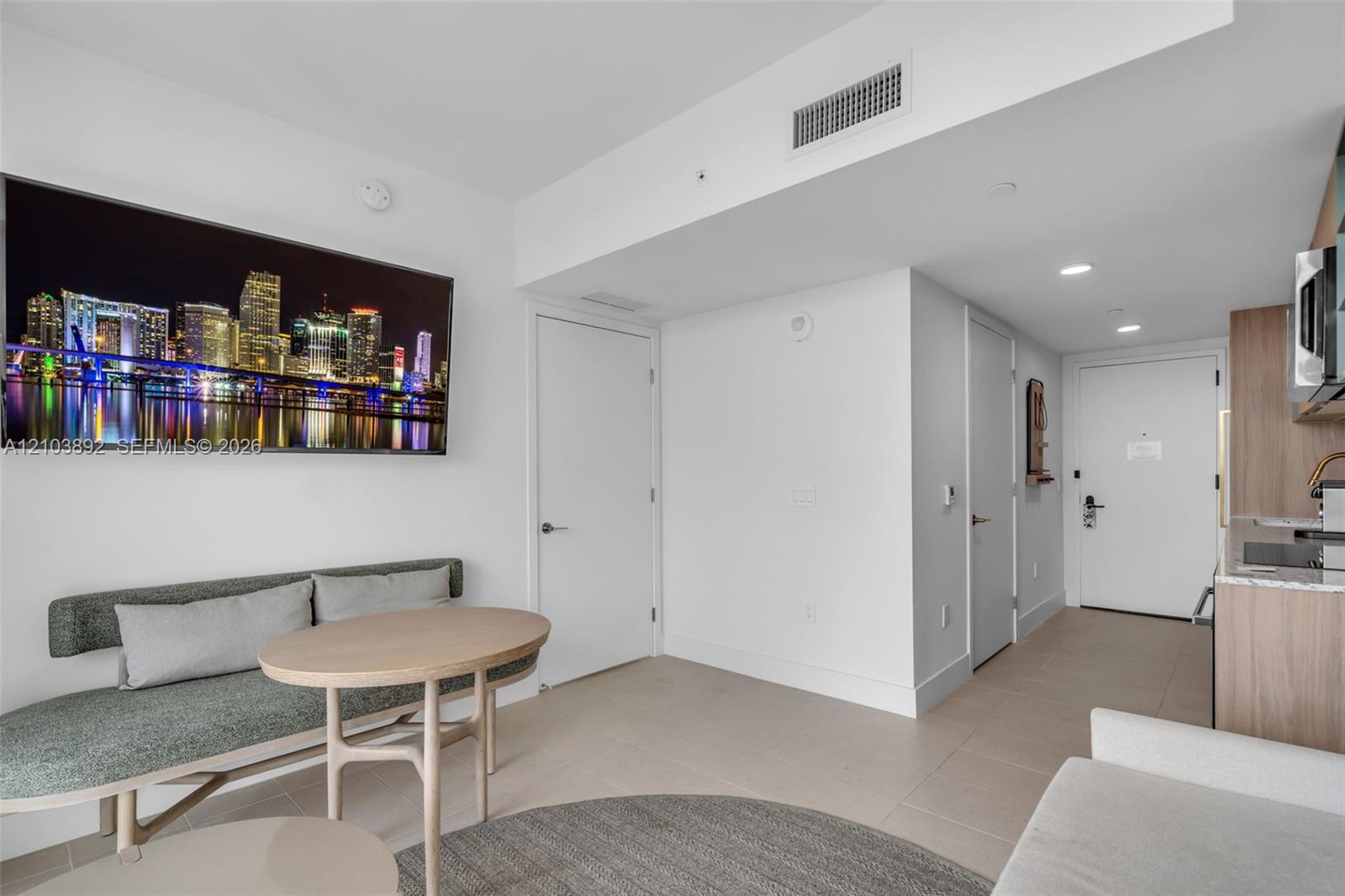 Neutral tone interior featuring large-format tile flooring, flat-panel wood-finish cabinetry, and recessed lighting
