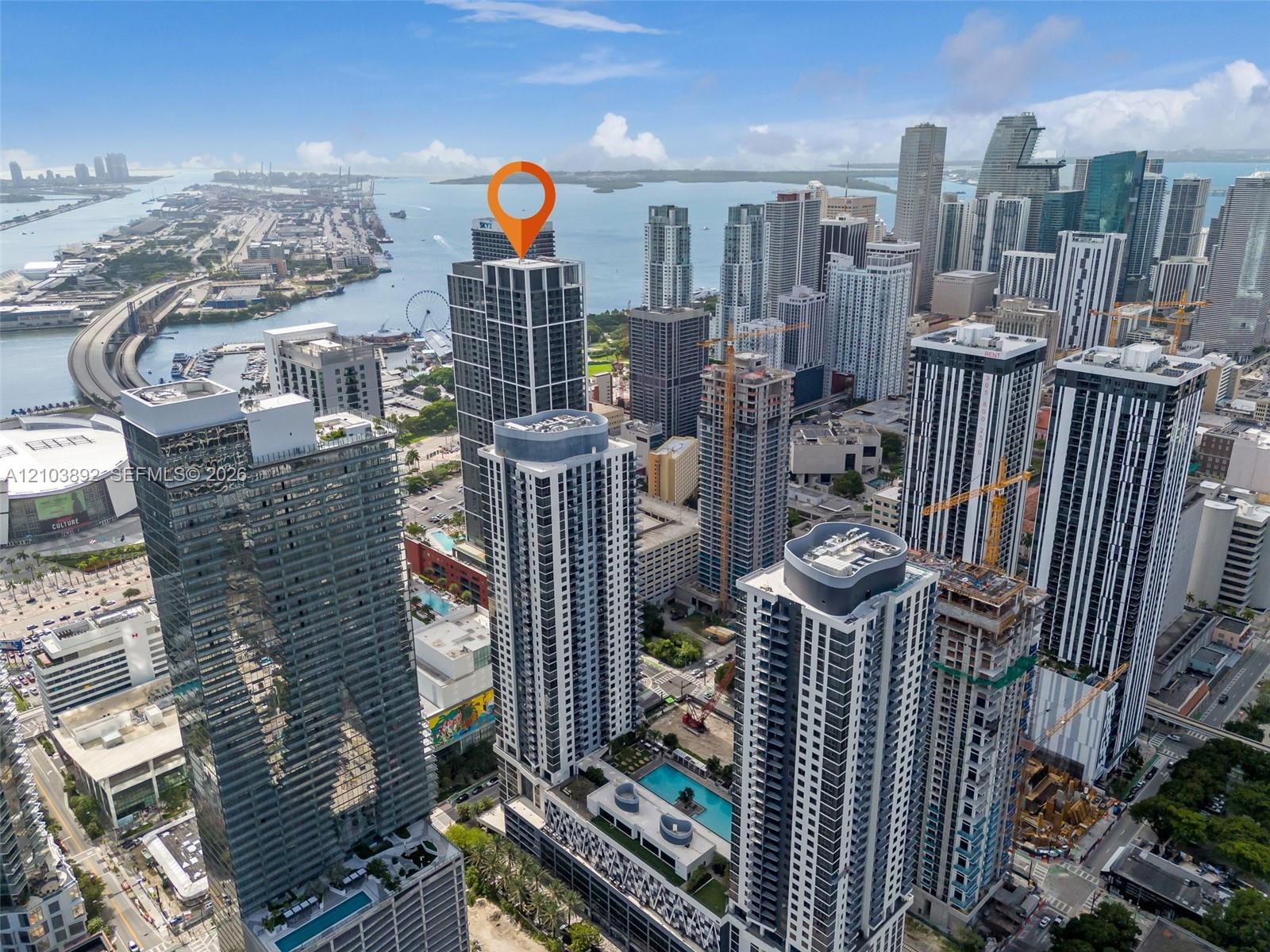 High-rise residential tower featuring a glass facade, podium-level swimming pool, and proximity to the waterfront and urban infrastructure