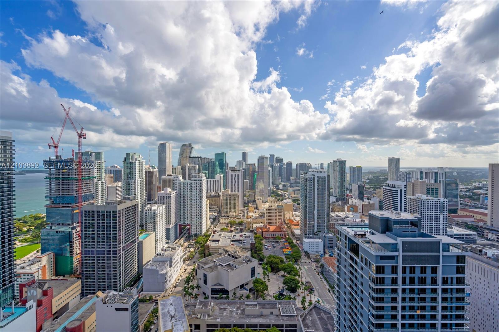 High-altitude urban perspective featuring expansive metropolitan skyline, coastal horizon, and dense architectural surroundings