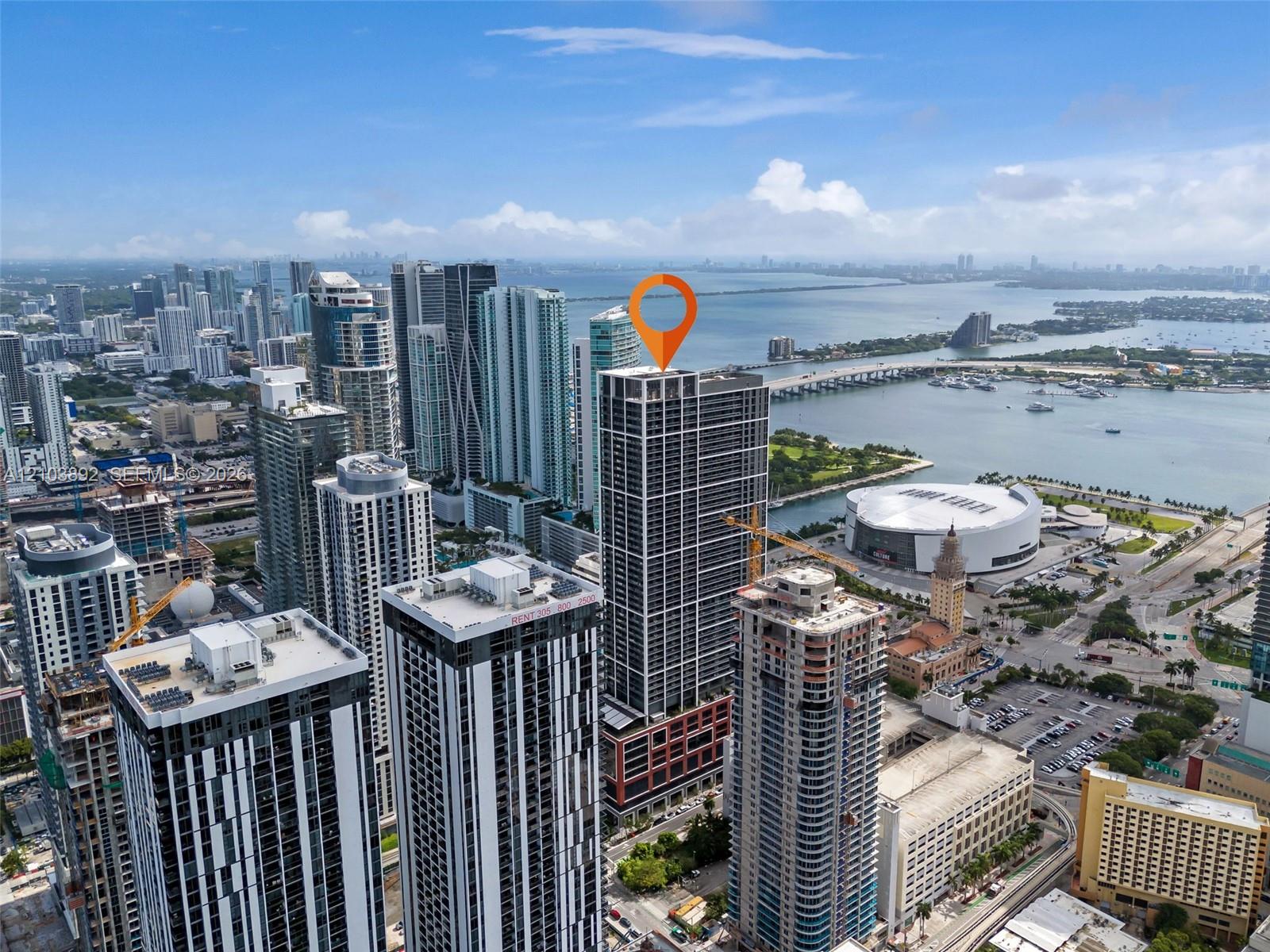 High-rise condominium building featuring a glass and concrete exterior, rooftop architectural elements, and urban positioning