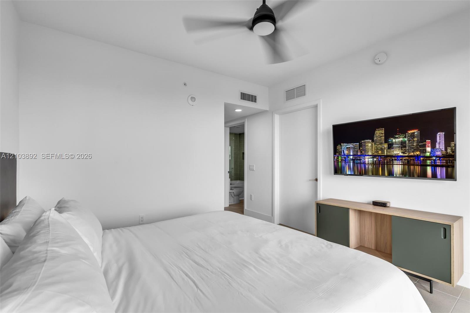 Interior room featuring a ceiling fan with integrated lighting, neutral wall finishes, and a built-in wall-mounted media console with cabinet storage