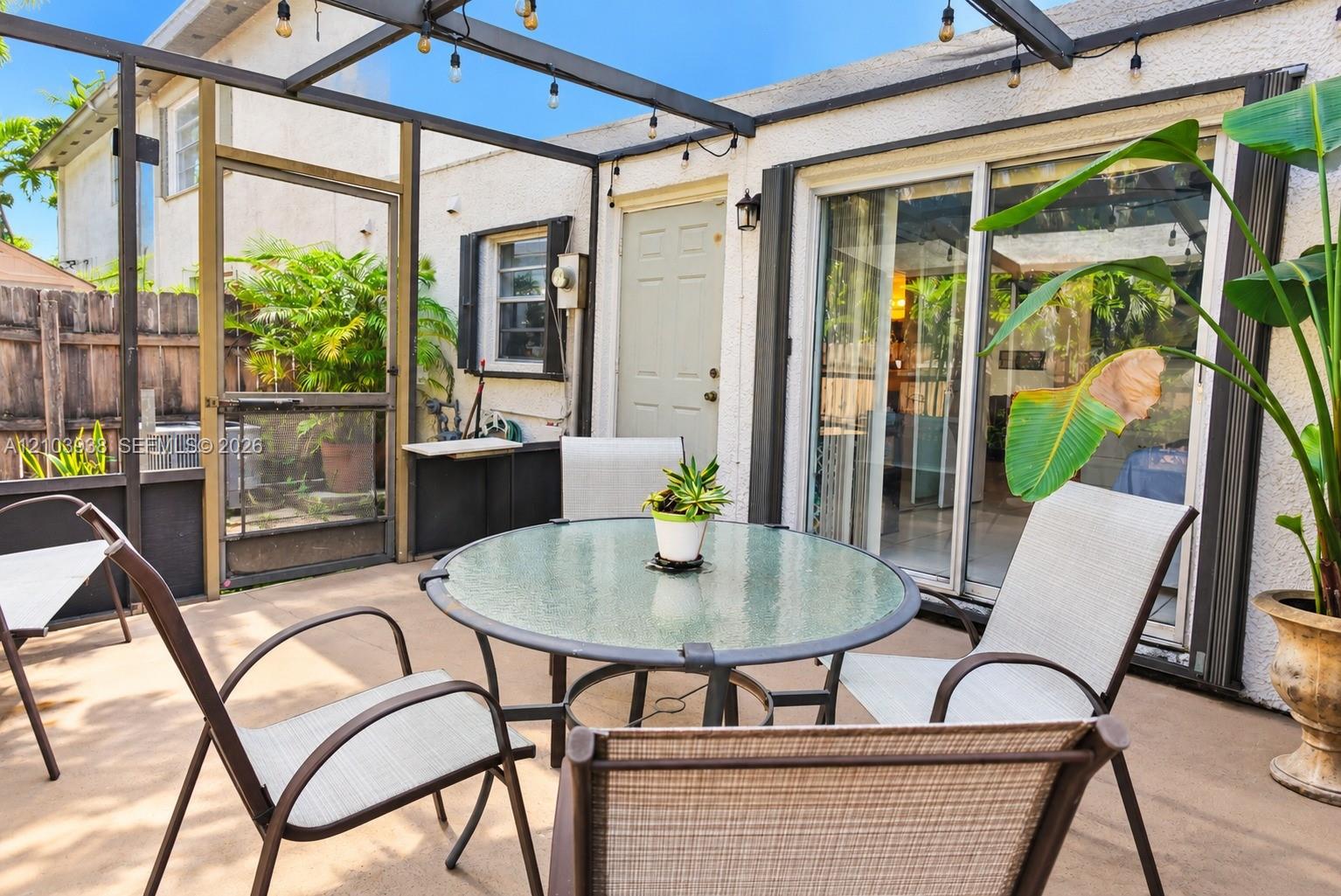 Screened-in patio featuring a concrete floor, dark metal structural framing, integrated string lighting, and sliding glass entry doors