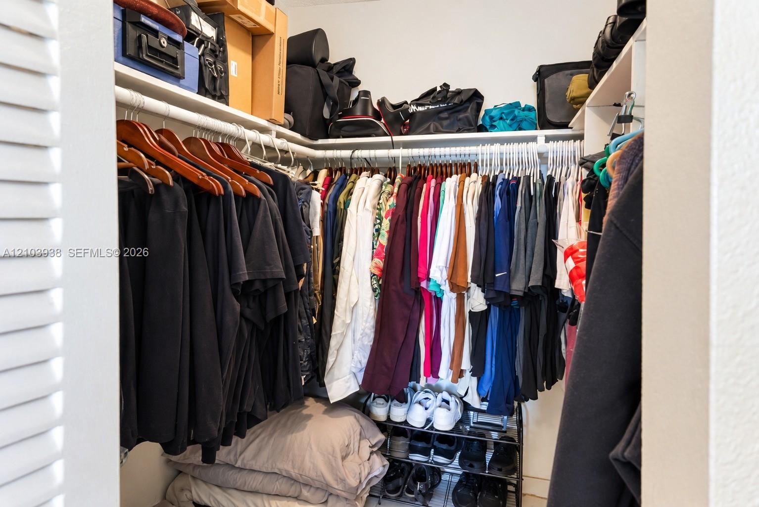 Walk-in closet featuring multi-level built-in shelving and dual-tier hanging rods
