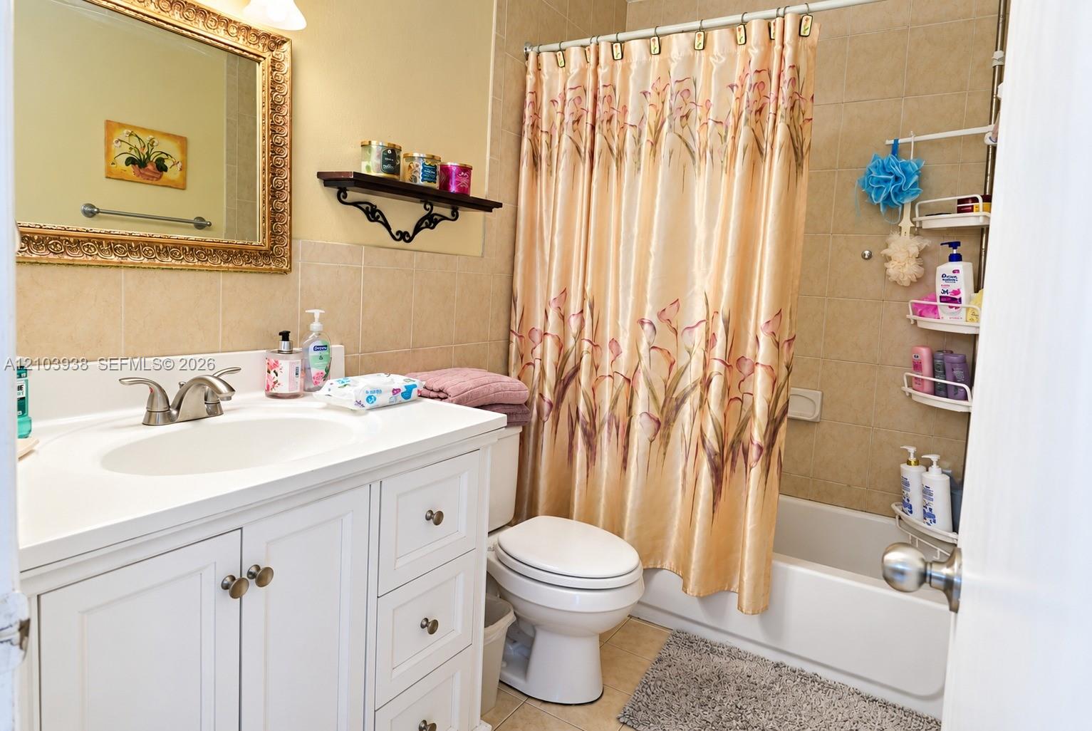 Bathroom featuring white cabinetry, an integrated sink with a dual-handle faucet, ceramic tile wall surround, and a tub-shower combination
