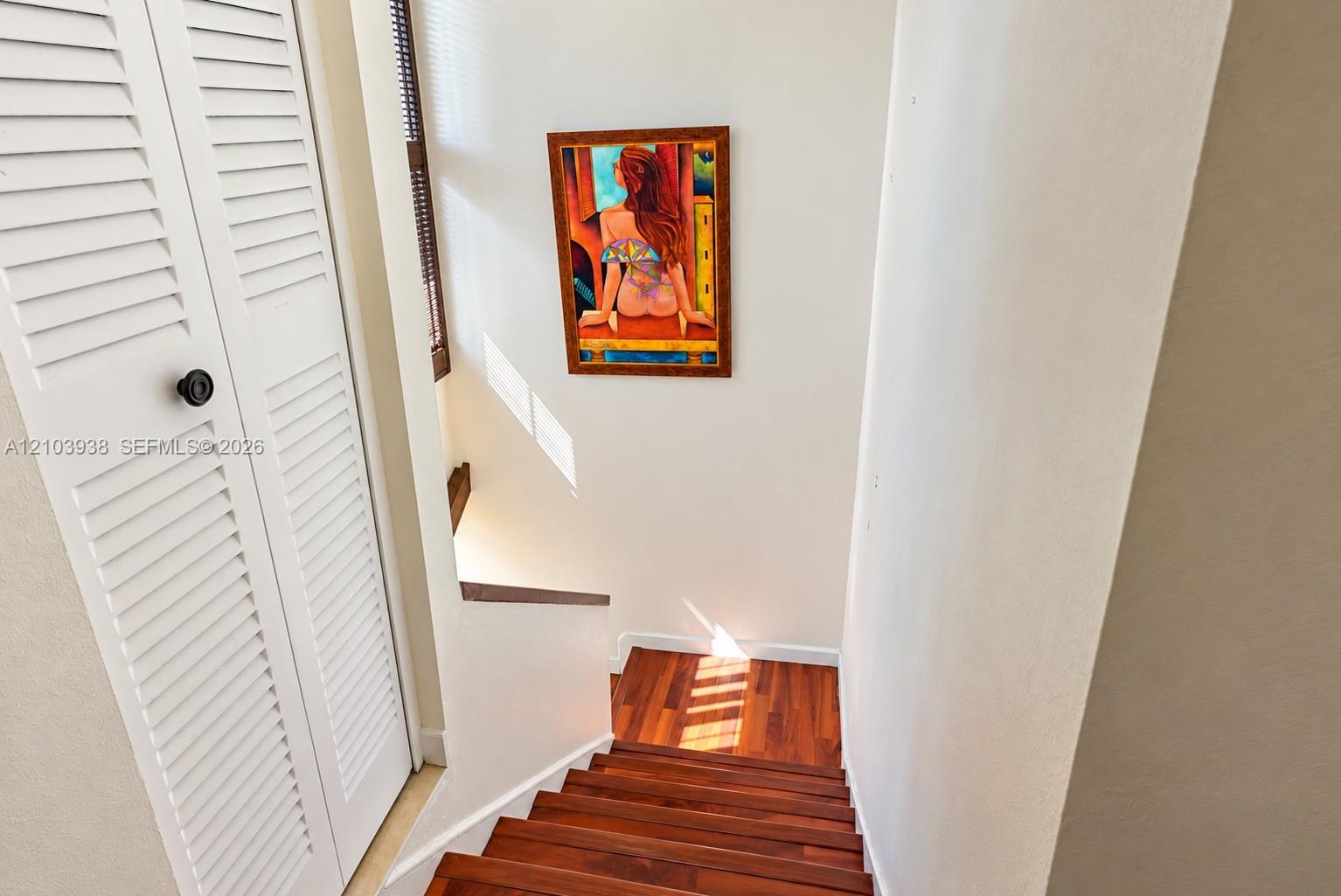 Staircase featuring wood-finish treads and white louvered bifold doors