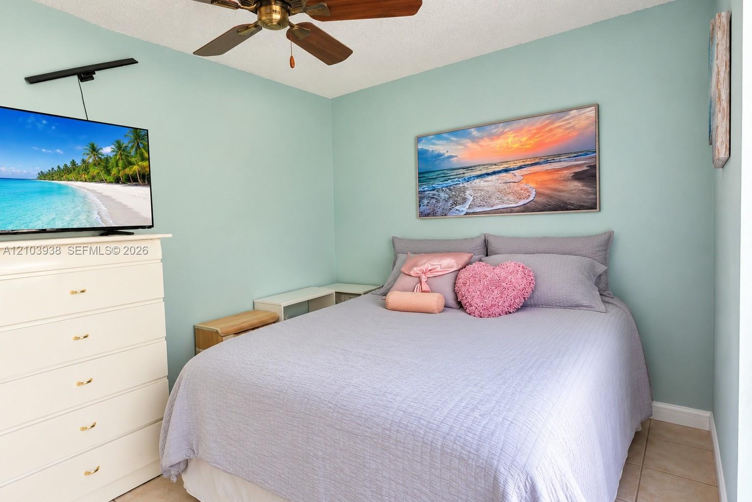 Bedroom featuring light blue wall paint, tile flooring, and a ceiling-mounted fan with dark wood-finish blades