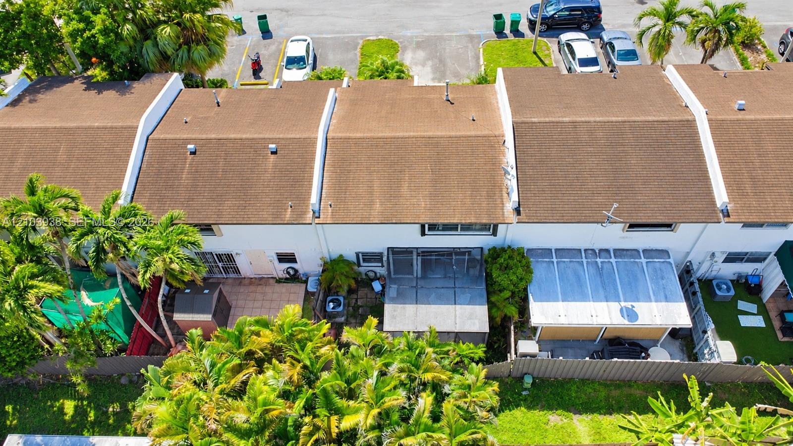 Aerial perspective of townhomes featuring shingled rooflines, exterior patios, screened-in enclosures, and lush perimeter landscaping