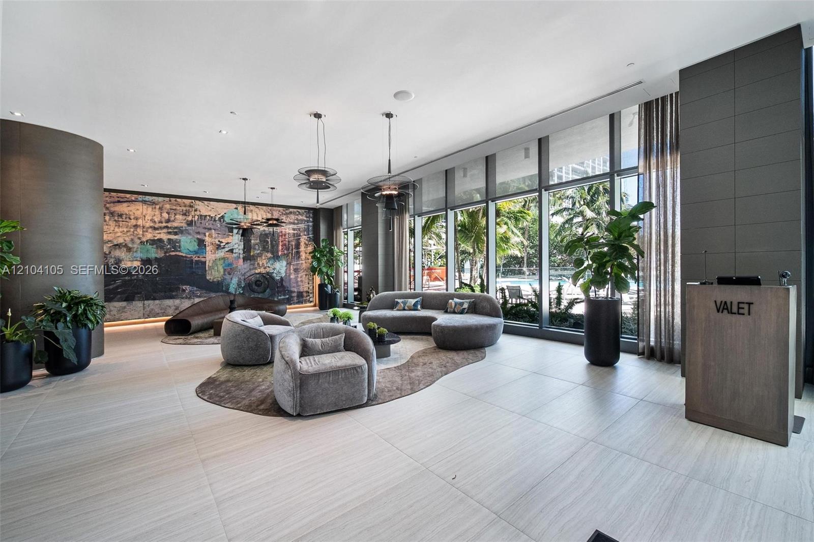 Expansive floor-to-ceiling windows, light-toned tile flooring, recessed ceiling lighting, and a valet station