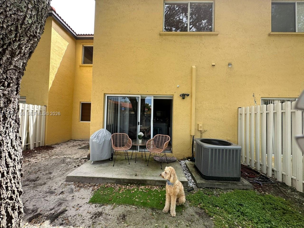 Stucco exterior featuring a rear concrete patio, sliding glass door, and vinyl privacy fencing