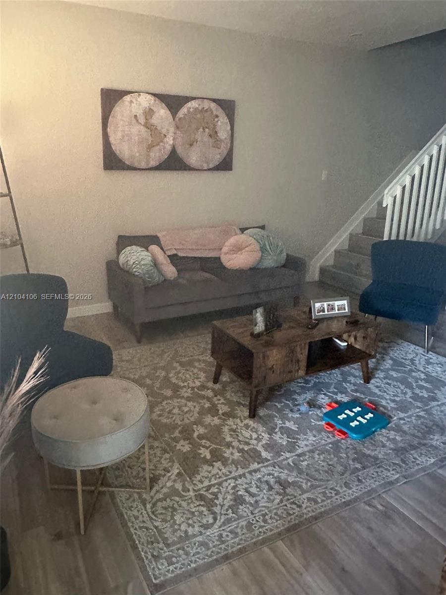 Wood-finish flooring, neutral wall tones, and staircase featuring white vertical balusters