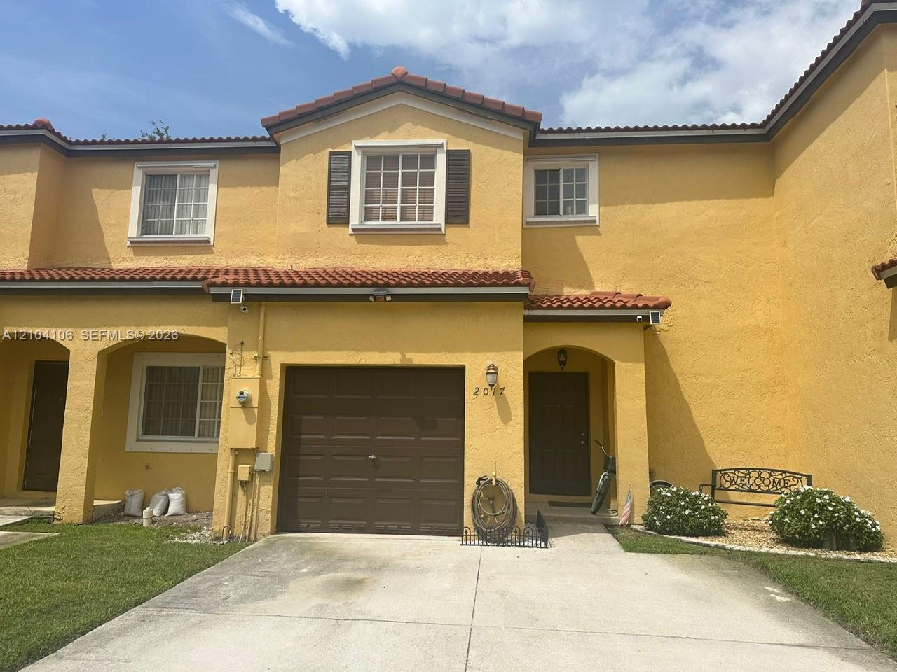 Stucco exterior featuring a terra cotta tile roof, recessed entryway, attached garage, and divided-lite windows with dark shutters Stucco exterior featuring a terra cotta tile roof, recessed entryway, attached garage, and divided-lite windows with dark shutters