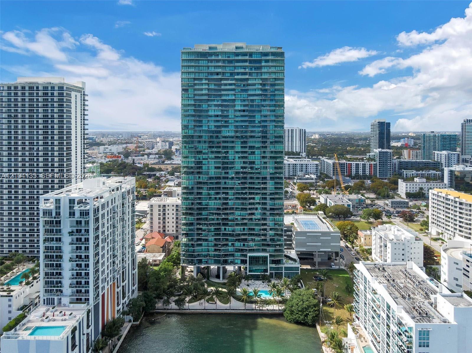 High-rise residential tower featuring a glass facade, private balconies, an on-site swimming pool, and direct waterfront positioning