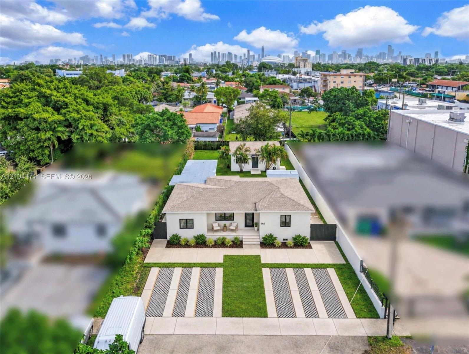 Single-story residence featuring a hipped roof, paved multi-car driveway with integrated turf ribbons, enclosed yard with solid perimeter fencing, and a detached structure