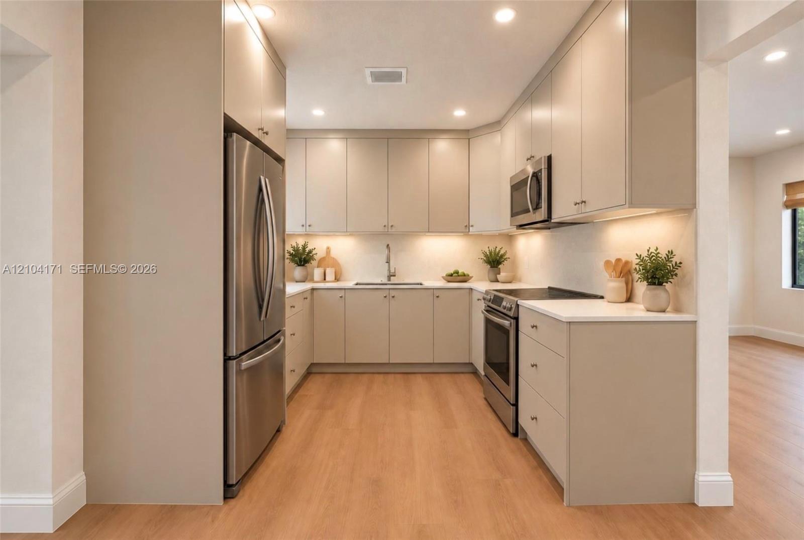 Kitchen featuring flat-panel cabinetry, light-toned countertops, recessed lighting, and stainless steel appliances including a refrigerator, range, and microwave