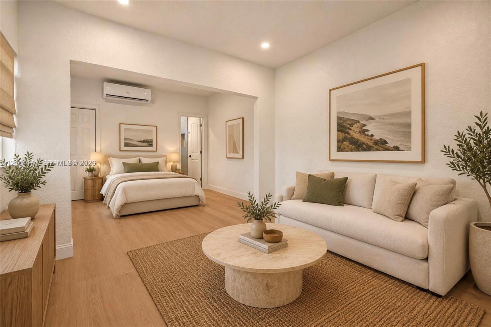 Open-concept living space featuring wood-finish flooring, recessed lighting, and a wall-mounted ductless air conditioning unit