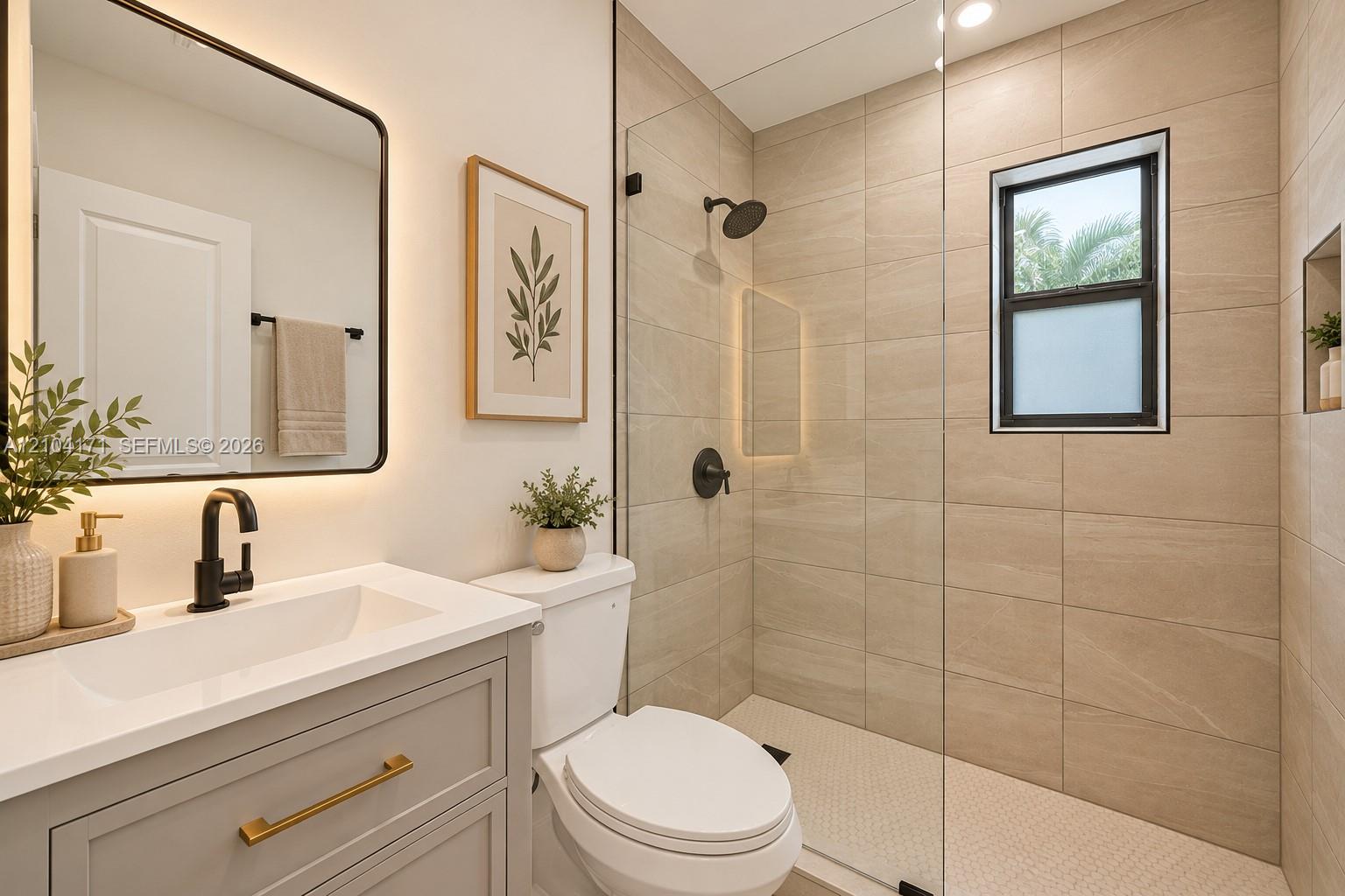 Bathroom featuring a light grey vanity with a white countertop, matte black fixtures, a walk-in shower with floor-to-ceiling tile, and a backlit rectangular mirror