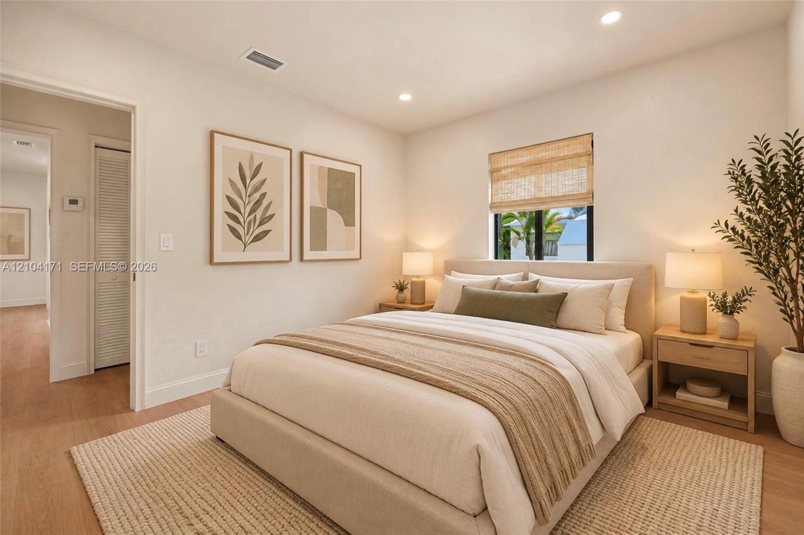 Neutral-toned interior featuring wood-finish flooring, recessed lighting, and a window with a woven shade