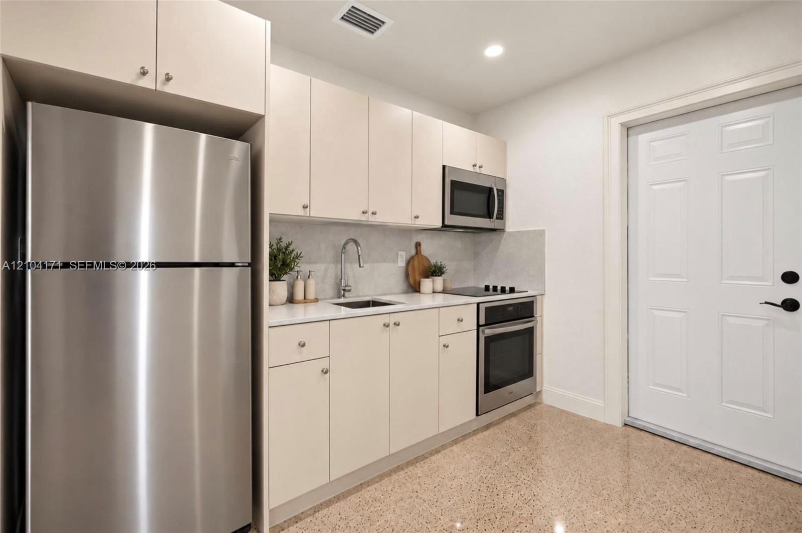 Kitchen featuring flat-panel cabinetry, stainless steel appliances, light-toned stone-finish countertops, and polished composite flooring