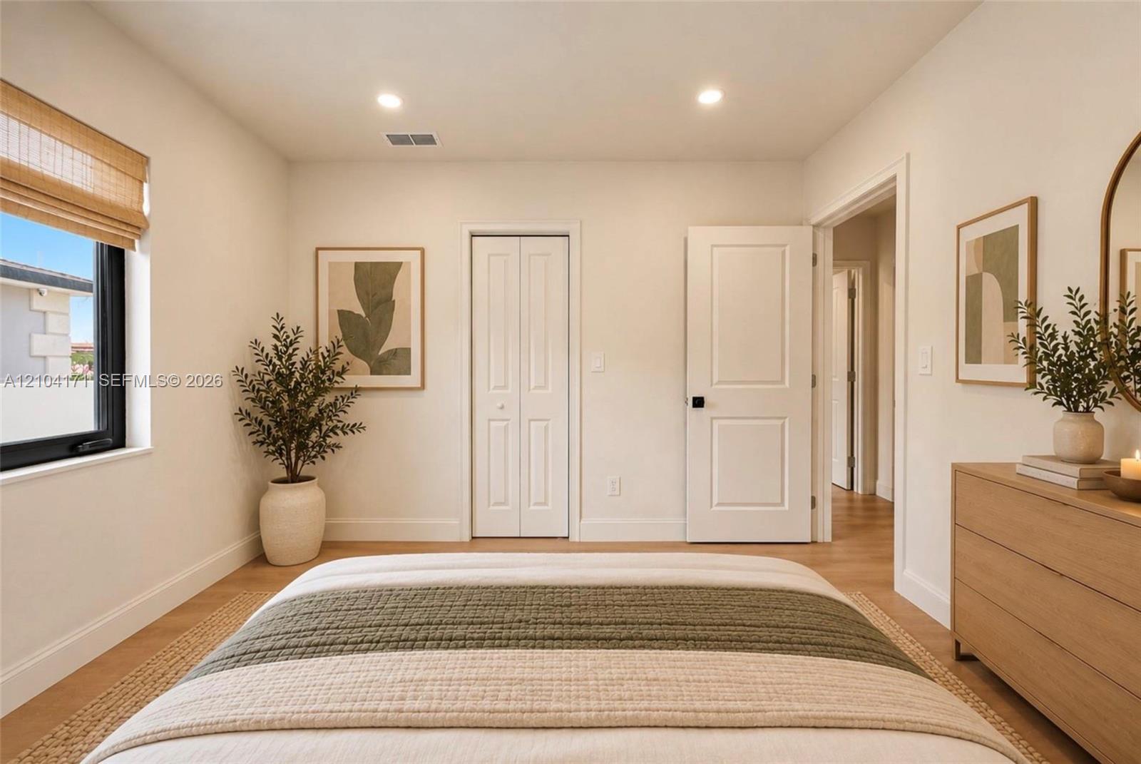 Neutral-toned interior featuring wood-finish flooring, recessed lighting, a single window with black framing, a bi-fold closet, and a multi-panel interior door with matte black hardware