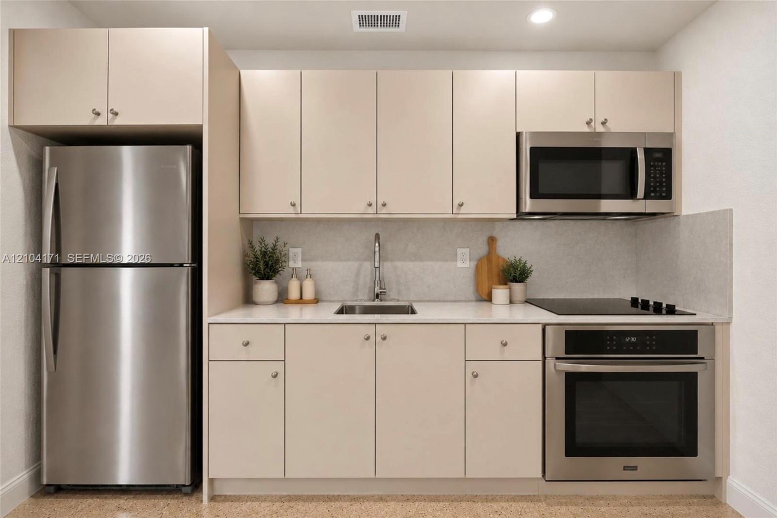 Kitchen featuring matte finish cabinetry, solid surface countertops, stainless steel refrigerator, built-in oven, and over-the-range microwave