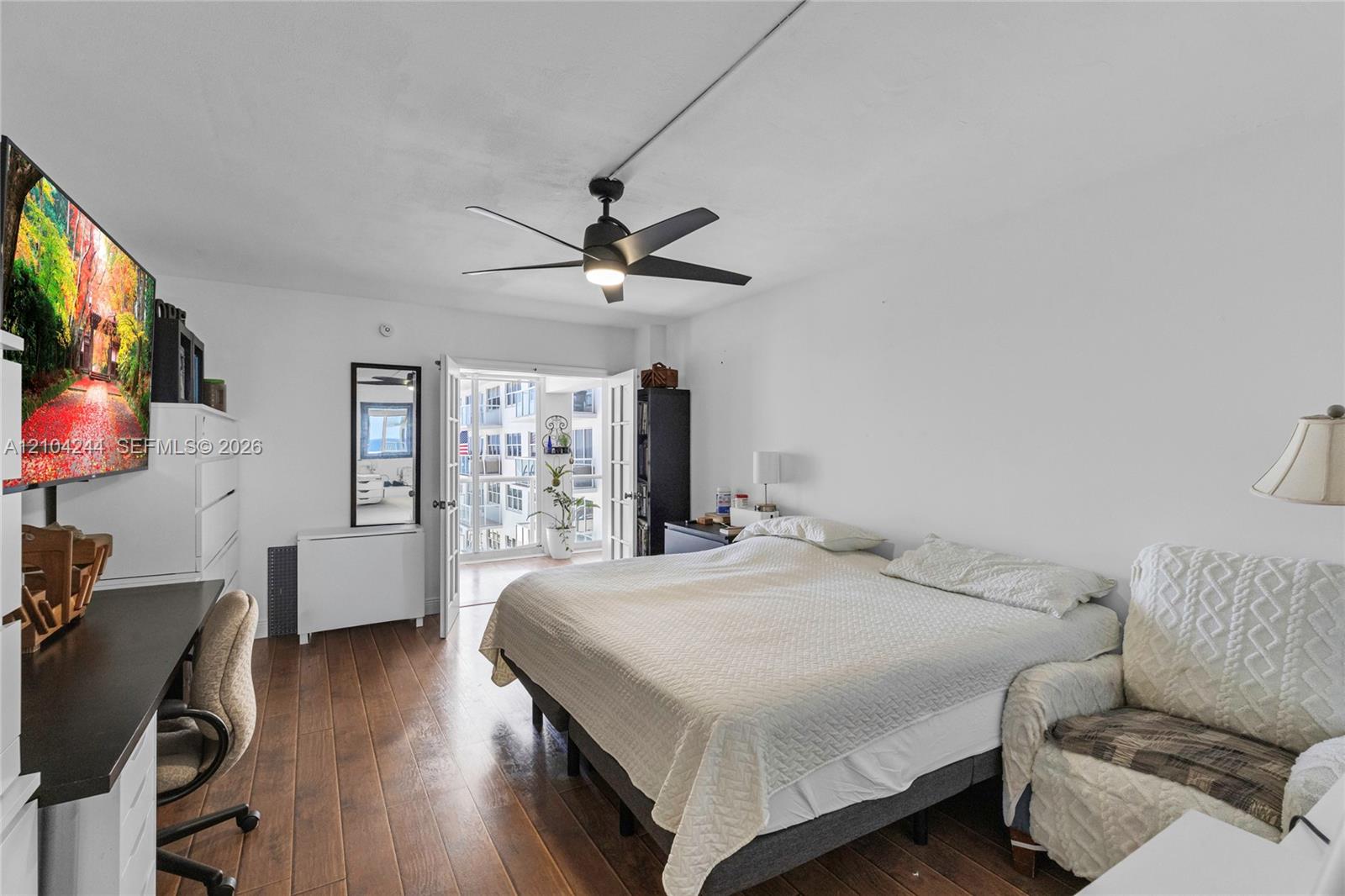 Wood-finish flooring, matte black ceiling fan with integrated lighting, and French doors