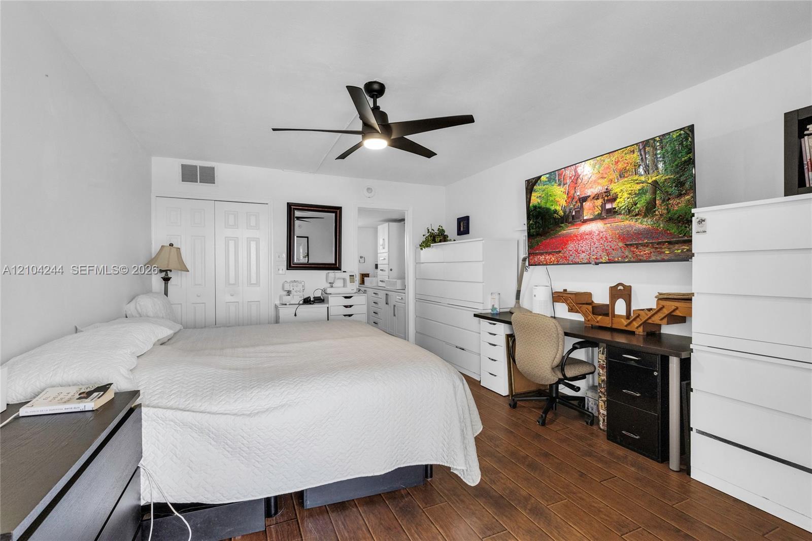 Wood-finish flooring, matte black ceiling fan, and double-door closet