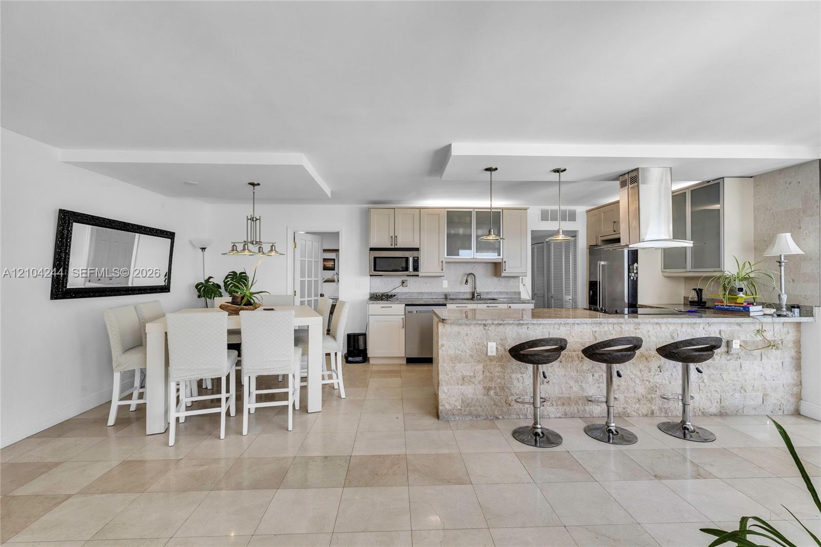 Kitchen featuring stone-finish cabinetry, stone-clad breakfast bar, stone flooring, stainless steel appliances, and tray ceilings