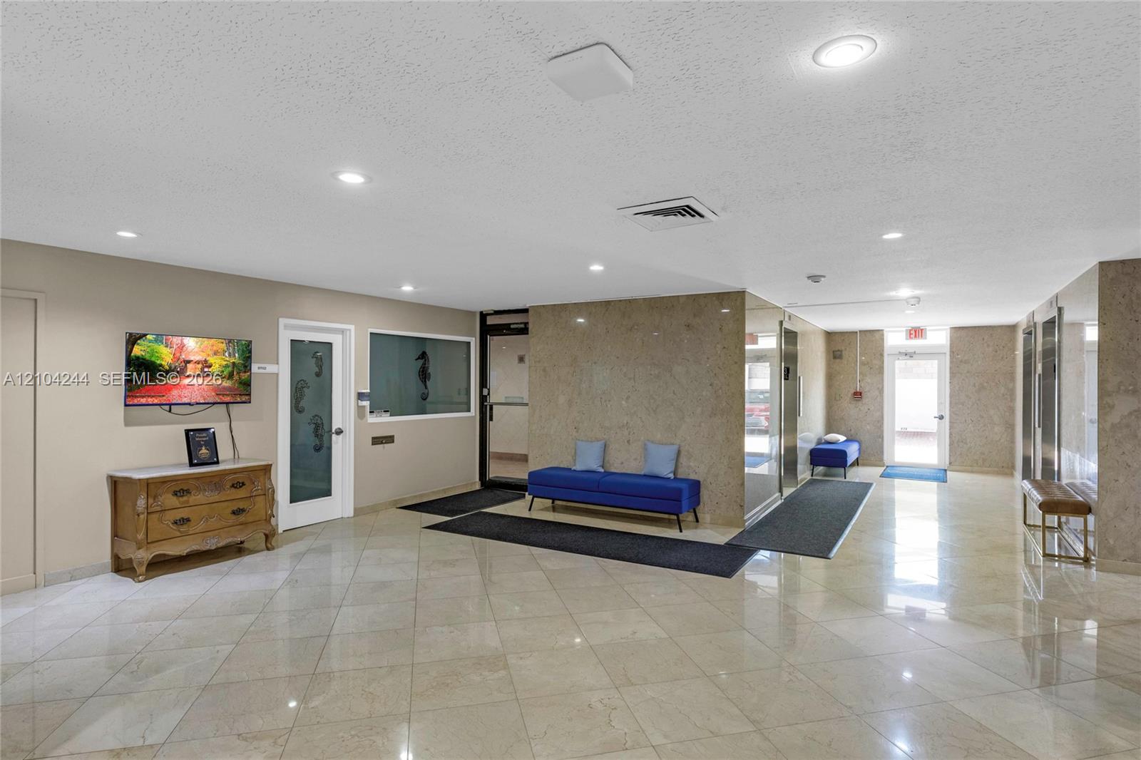 Lobby featuring polished stone floor tiling, stone-clad wall accents, recessed lighting, and metal elevator doors