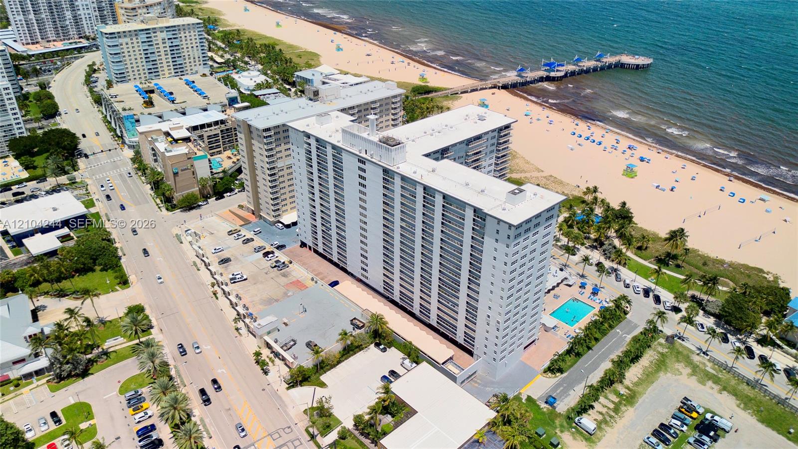 High-rise condominium building featuring direct oceanfront positioning, an outdoor swimming pool, and gated surface parking
