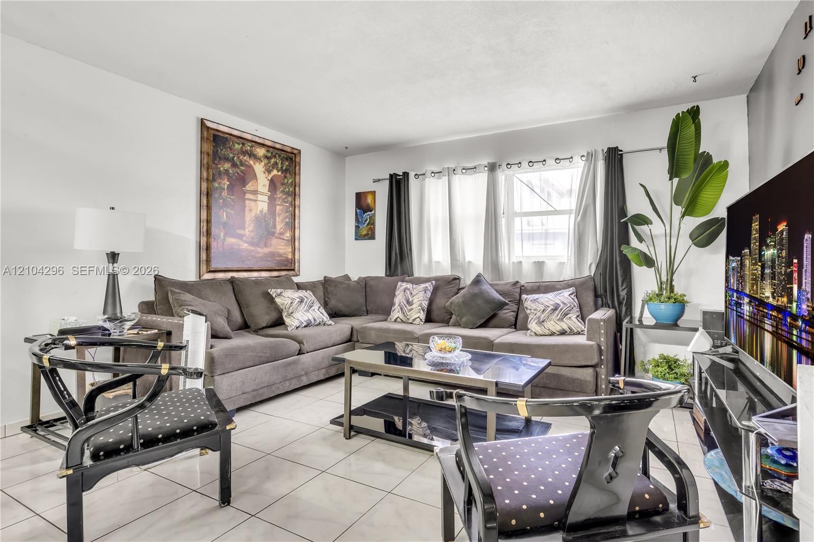 Living area featuring ceramic tile flooring, neutral wall tones, and large window with metallic rod hardware