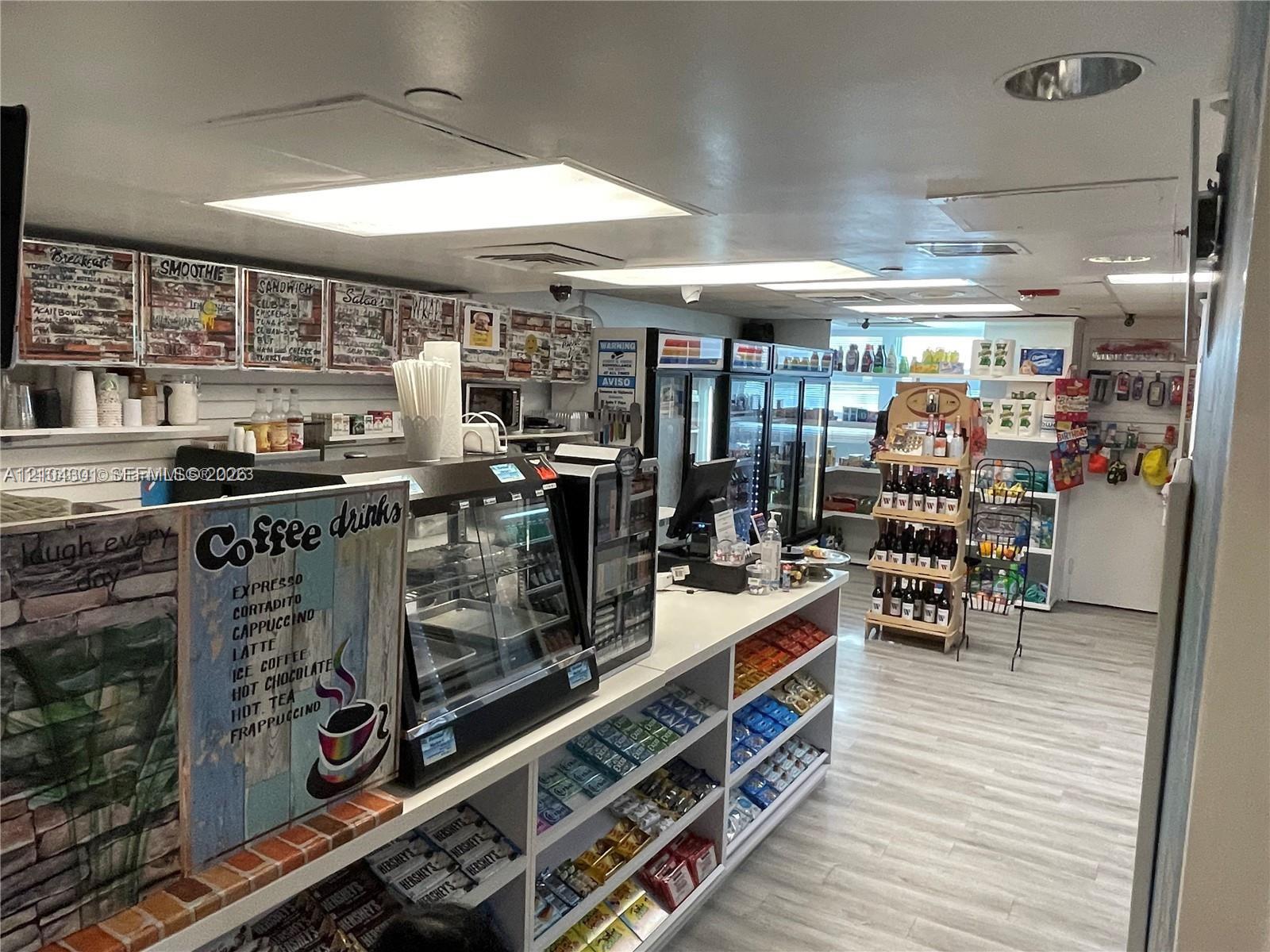 Retail space featuring integrated slat-wall shelving, recessed lighting, wood-finish flooring, and commercial-grade glass refrigeration units