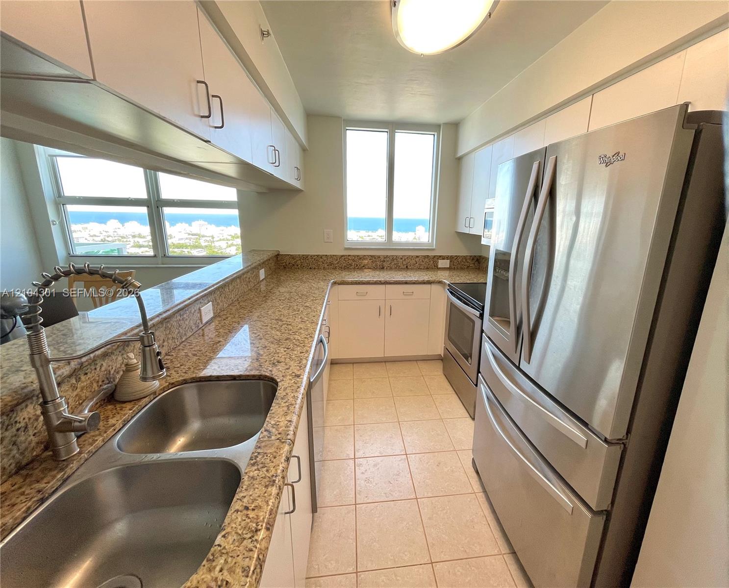 Kitchen featuring stainless steel appliances, stone-finish countertops, dual-basin under-mount sink with pull-down faucet, white cabinetry, and ceramic tile flooring Kitchen featuring stainless steel appliances, stone-finish countertops, dual-basin under-mount sink with pull-down faucet, white cabinetry, and ceramic tile flooring