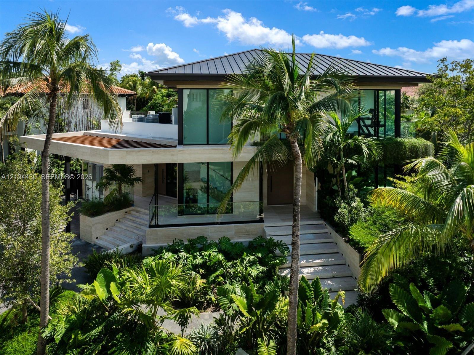 Contemporary residence featuring floor-to-ceiling glass windows, stone cladding, a standing-seam metal roof, integrated glass terrace railings, and stone staircases