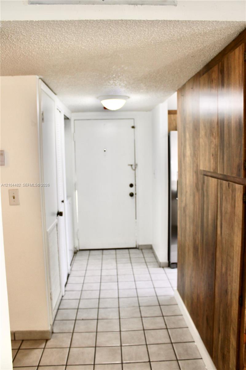 Entryway featuring square ceramic tile flooring, wood-finish wall paneling, built-in cabinetry, and a flush-mount ceiling light fixture