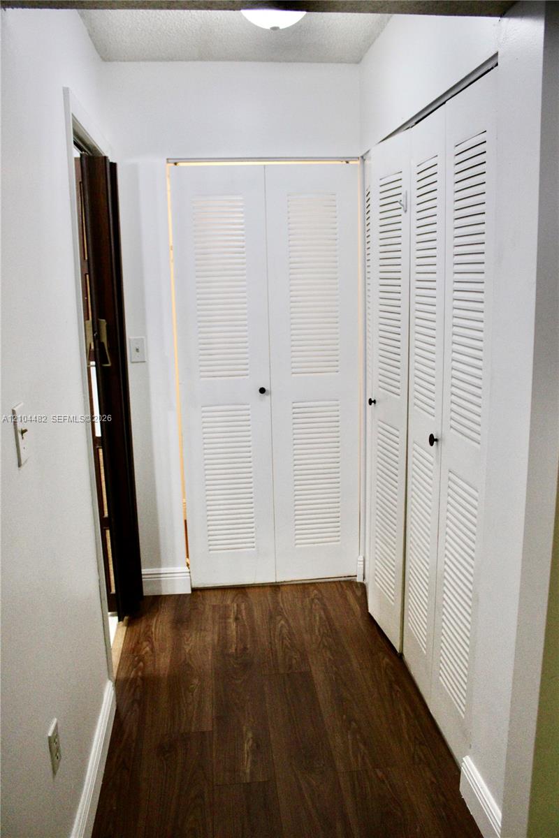 Hallway featuring wood-finish flooring and multiple white louvered bifold doors
