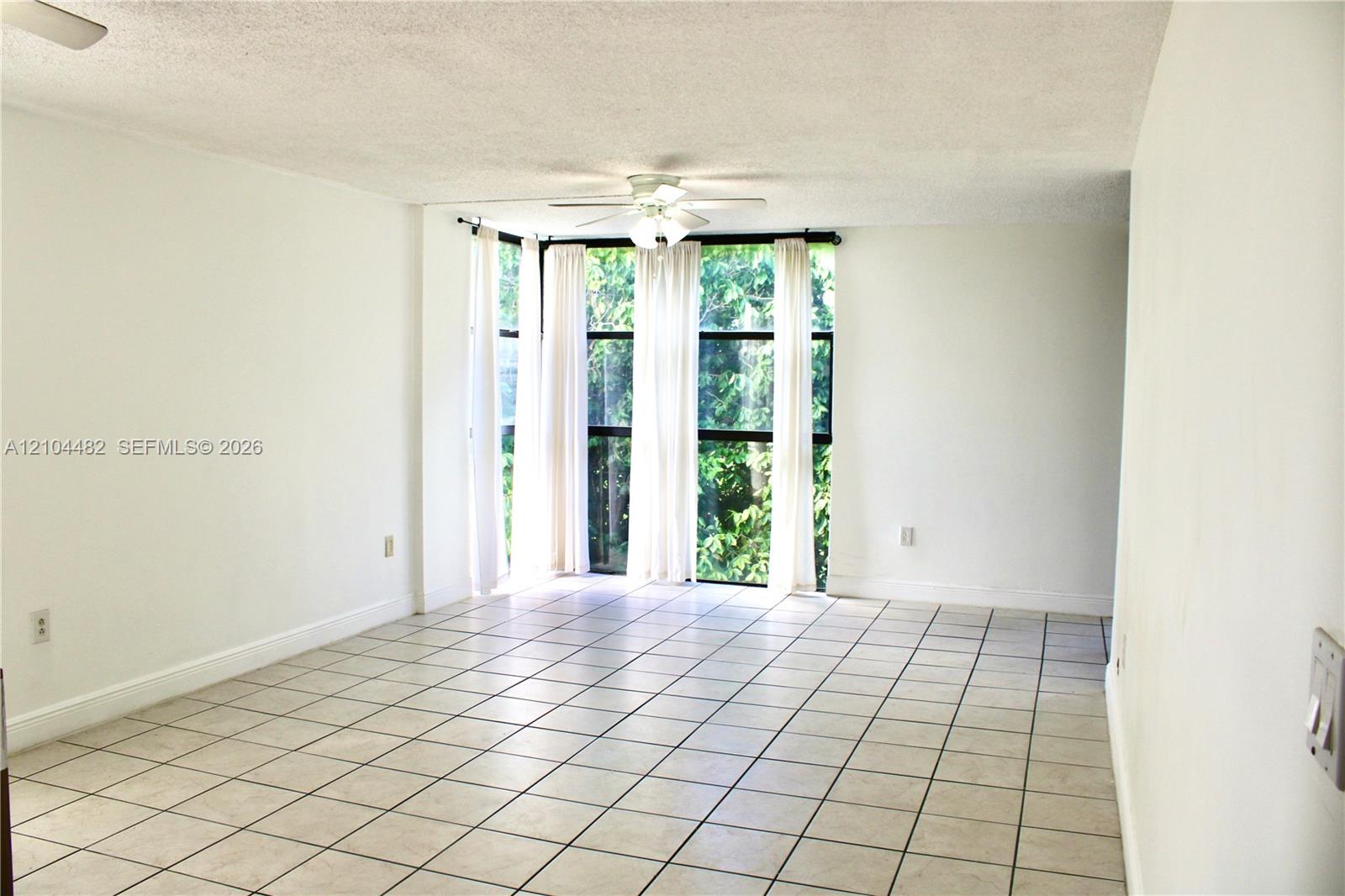 Interior space featuring ceramic tile flooring, a multi-panel floor-to-ceiling window arrangement, and a centrally mounted ceiling fan