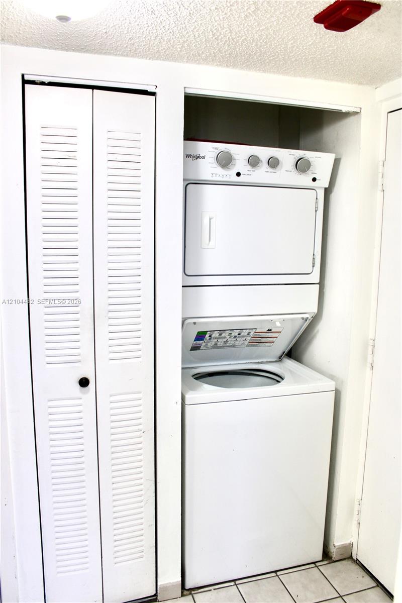 Stackable laundry unit featuring a white finish and louvered bi-fold closet doors