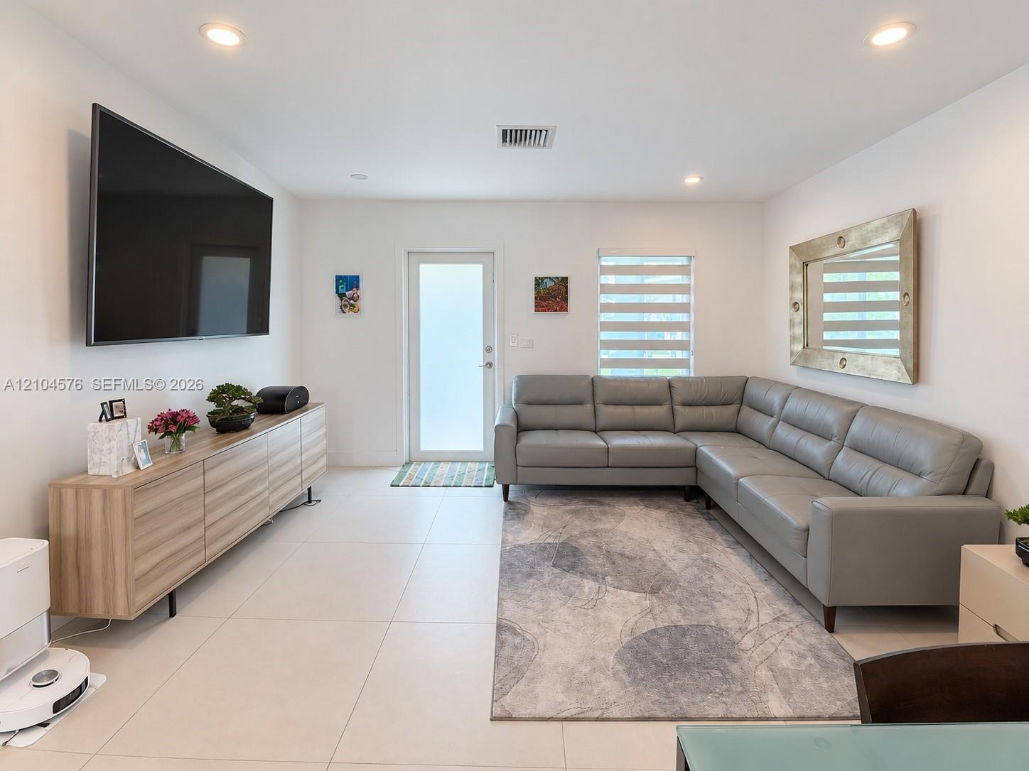 Large-format tile flooring, recessed lighting, and dual-shade window coverings featuring a glass-panel entry door Large-format tile flooring, recessed lighting, and dual-shade window coverings featuring a glass-panel entry door