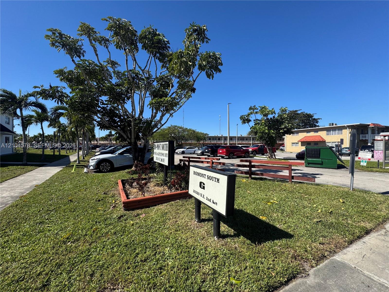 Property exterior featuring paved parking areas, concrete walkways, mature landscaping, and signage Property exterior featuring paved parking areas, concrete walkways, mature landscaping, and signage