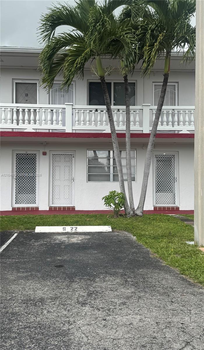 Two-story exterior featuring white stucco finish, second-level balustrade balcony, and assigned surface parking space Two-story exterior featuring white stucco finish, second-level balustrade balcony, and assigned surface parking space