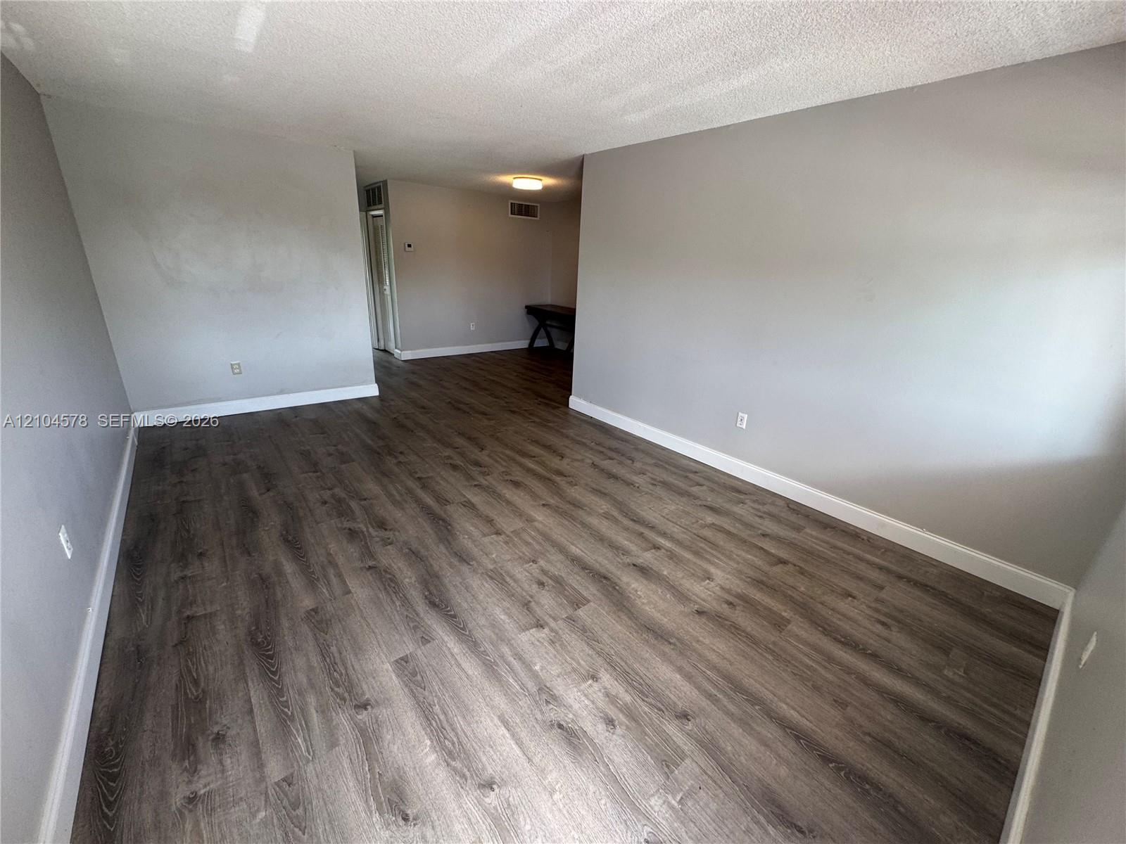 Wood-finish flooring throughout, stainless steel refrigerator, white cabinetry, and exterior door with glass insert Wood-finish flooring throughout, stainless steel refrigerator, white cabinetry, and exterior door with glass insert