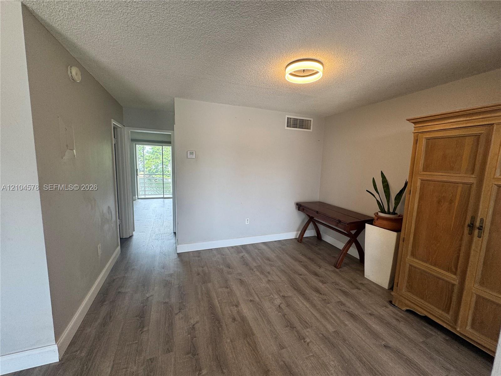 Neutral interior featuring wood-finish flooring and a circular flush-mount ceiling fixture Neutral interior featuring wood-finish flooring and a circular flush-mount ceiling fixture